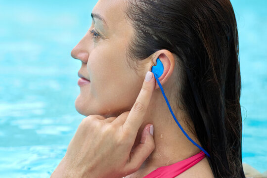 Close-up view of a woman using individual earplugs while swimming, ensuring sound protection while enjoying pool water. Hearing protection solutions