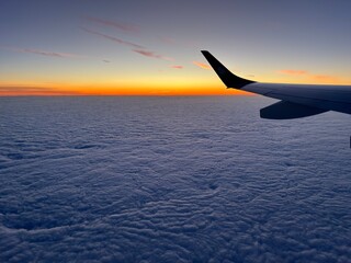 Sunrise over a layer of clouds from a plane window