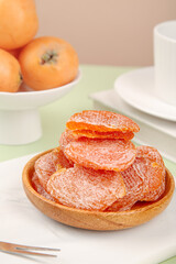 Dried persimmon fruit slices with sugar coating in wooden bowl, healthy natural snack food