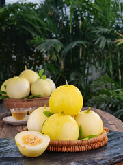 Fresh Yellow Melons in Wicker Basket on Wooden Table with Tropical Garden Background