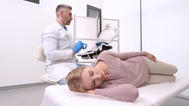 Sonographer examines brain of female patient by placing ultrasound transducer on temple of patient's head. Vascular ultrasound of migraine