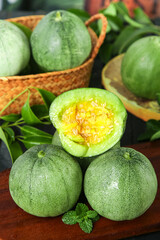 Fresh Shandong Emerald Melons in Wicker Basket with Cut Open Melon Showing Yellow Flesh