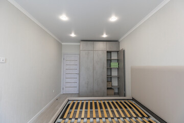 Scandinavian inspired closet shelf detail with woven baskets and cream plastic containers on grey shelving, near gray patterned boxes in a clean minimalist wardrobe setup.