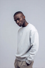 young man in gray sweatshirt exudes focus and determination against clean background