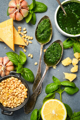 Pesto sauce. Metal spoon with traditional pesto sauce on a gray stone background. Close-up.