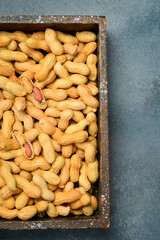 Wooden box filled with unshelled peanuts. On a gray concrete background. Nuts Close-up.