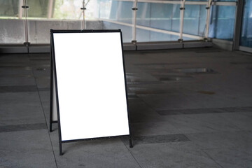 Blank white outdoor advertising stand sandwich board mock up template. Clear street signage board placed by an outdoor dinning area of a restaurant.