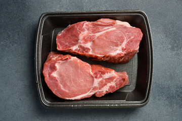 Raw meat. Fresh pork steak. Meat on a plastic black container from the market. Close-up.