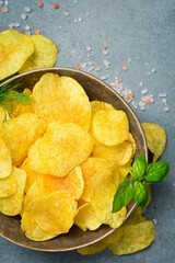 Beer snacks. Ceramic bowl with potato chips. Top view, on a stone background.
