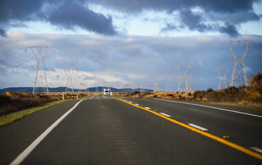 Fototapeta premium Power pylons and power lines on both sides of the Desert Road. Truck driving on the road. North Island. New Zealand.