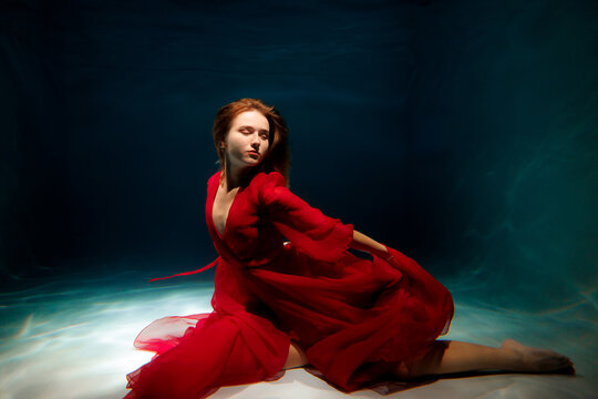 Dance in a flowing red dress captured underwater at midday