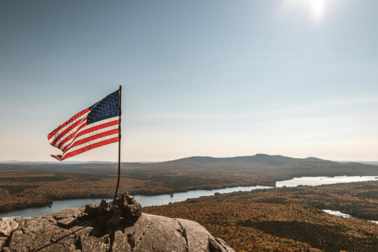 American flag blowing in wind at summit of mountain in fall, Maine