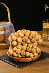 Fresh Baby Potatoes in Wicker Basket on Rustic Kitchen Table with Tea and Bread