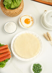 Fresh Ingredients for Handmade Spring Rolls with Vegetables and Flour on White Background