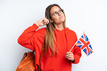 Young hispanic woman holding an United Kingdom flag isolated on white background having doubts and...