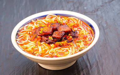 Spicy Asian Noodle Soup with Handrolled Noodles and Braised Meat in Traditional Bowl