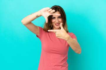 Fototapeta premium Young caucasian woman isolated on blue background focusing face. Framing symbol
