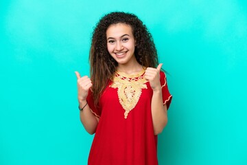 Young Arab woman isolated on blue background with thumbs up gesture and smiling