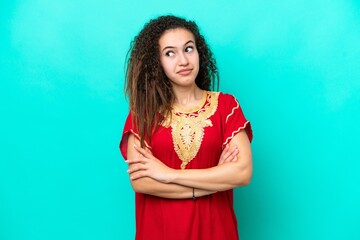 Young Arab woman isolated on blue background making doubts gesture while lifting the shoulders