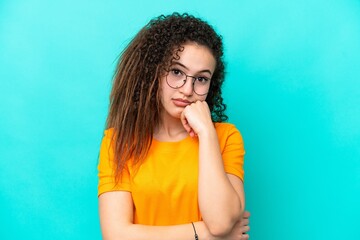 Young Arab woman isolated on blue background With glasses and with sad expression