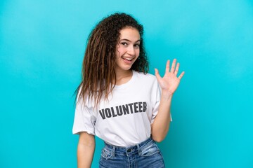 Young Arab volunteer woman isolated on blue background saluting with hand with happy expression