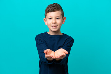 Little kid boy isolated on blue background holding copyspace imaginary on the palm to insert an ad