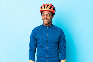 Young cyclist man with braids over isolated background having doubts while looking up