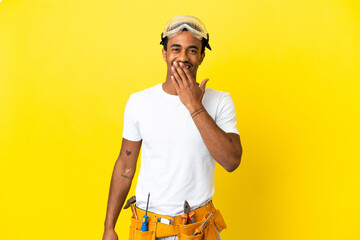 African American electrician man over isolated yellow wall happy and smiling covering mouth with hand