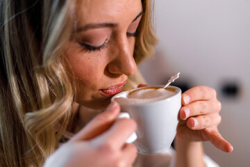 Woman enjoying a warm cup of coffee in a cozy setting while savoring the aroma
