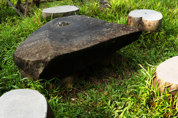 Rustic stone table sits among grass surrounded by round seats