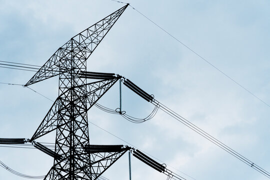 Black lattice power lines stretch across pale blue sky structure