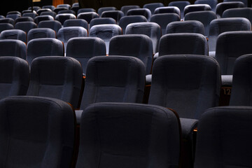 Naklejka premium Karachi, Pakistan - April 10, 2025: A captivating view of multiple rows of empty seats under dim lighting, Ideal for concepts related to education, presentations, cinema, events, or public gatherings.
