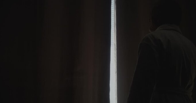 Gray Haired Mature Man Stretches and Opens Window Curtains in Hotel Room as Sunlight Floods in. Calm Smile Captures Beauty of Simple Moments. Concept of Self Care, Slow Mornings, and Travel Serenity.