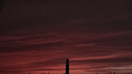 Time lapse clouds over the city at sunset, showing an orange and blue sky with industrial silhouettes.