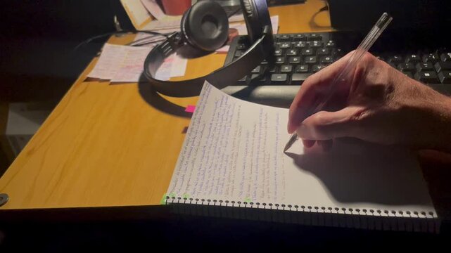 escribiendo a mano l&iacute;nea y frase en cuaderno con bol&iacute;grafo sobre el escritorio de madera de la habitaci&oacute;n
