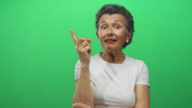 Senior woman with grey hair gestures idea against a vibrant green background, wearing a white shirt and showing thoughtful and surprised expressions in a sequence of frames.