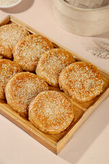 Traditional Chinese Sesame Seed Pastries in Bamboo Steamer - Beijing Style Sweet Desserts with Crispy Golden Coating