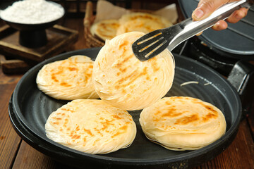 Chinese Layered Flatbread Cooking in Pan with Tongs - Traditional Breakfast Bread