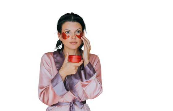 Brunette woman first time placing face cosmetic patches on face on transparent background. Cosmetics, skincare, women beauty. Female in nightgown doing skin care procedure.