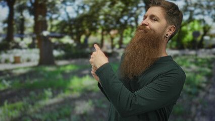 Man with long beard standing finger pointing toward sunlit green forest path; exploration curiosity.