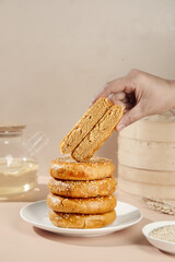 Hand Stacking Traditional Chinese Sesame Cakes Beijing Style Dessert Pastries on White Plate