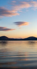 Serene Lake Sunset with Mountain Silhouettes and Colorful Clouds.
