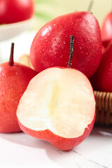 Fresh Red Shaanxi Pears with Water Droplets Cut Half Showing White Flesh in Wicker Basket