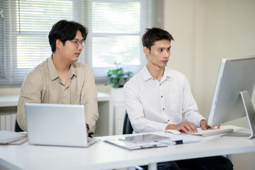 Obraz premium Two male office workers are discussing work in the office.