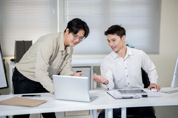 Fototapeta premium Two male office workers are discussing work in the office.