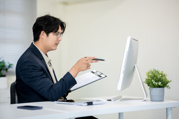 Male office worker checking documents on computer desk in office