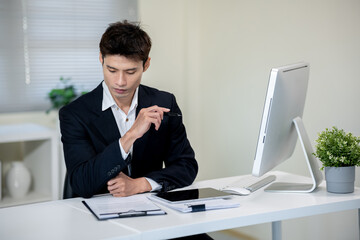 Male office worker checking documents on computer desk in office