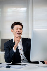 A male office worker is presenting work to a client on a computer in the office.