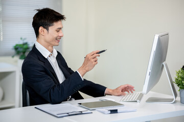 A male office worker is presenting work to a client on a computer in the office.