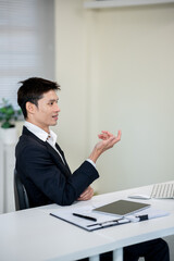A businessman is discussing work with a client at a desk in an office.